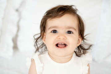 Portrait of a baby girl, smiling newborn little baby on a bed at home laughing