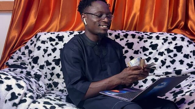 Black handsome Man excited by how much money  he is making using laptop technology.