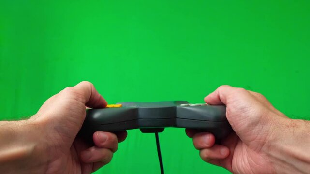 A close-up shot of hands actively holding and operating controller against a vibrant green screen background. The thumbs are positioned over the joystick and various buttons, indicating immersive game