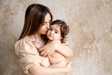 a mother with a baby, a young mom gently hugs and kisses her newborn baby, holding him in her arms, maternal love and care, a mother having fun with her child at home