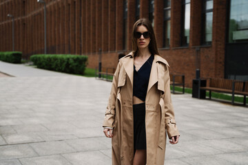 Obraz premium Young pretty beautiful woman in trench coat and sunglasses