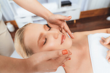 Fototapeta premium Caucasian woman enjoying relaxing anti-stress head massage and pampering facial beauty skin recreation leisure in dayspa modern light ambient at luxury resort or hotel spa salon. Quiescent
