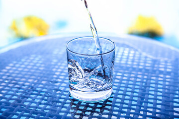 close up pouring water to glass on the glass table in outdoor