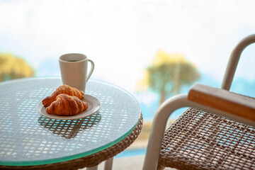 Outdoor coffee table with croissant and drink in outdoor on close range. Cup of tea, fresh baked croissants.