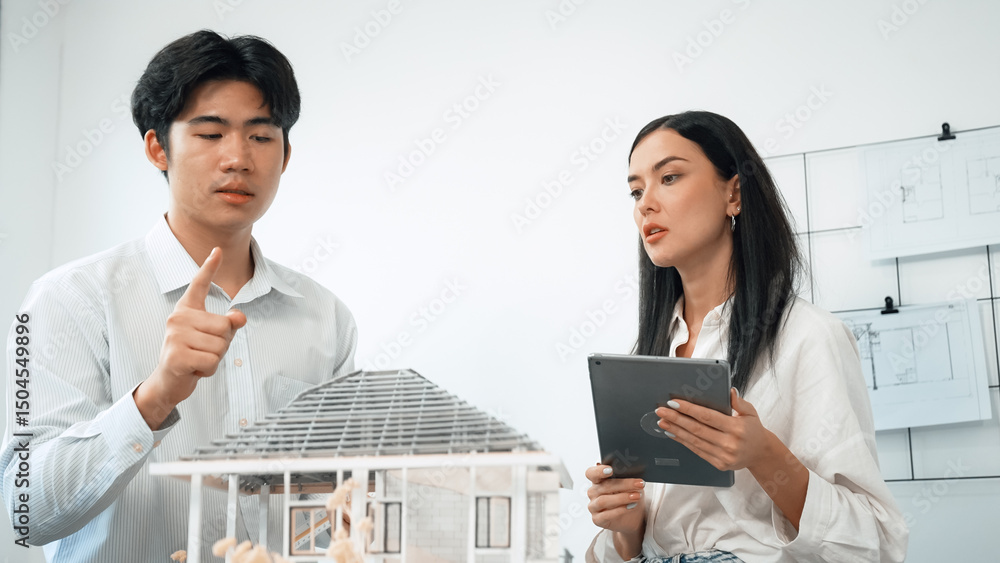 Poster beautiful young caucasian project manager tells asian engineer about building detail by using tablet