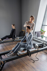 Fototapeta premium Woman training pilates on the reformer bed. Reformer pilates studio machine for fitness workouts in gym. Fit, healthy and strong authentical body. Fitness concept