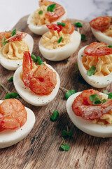 Boiled eggs stuffed with yolk and seasoned with mayonnaise, stuffed eggs with shrimp, on a wooden chopping board, selective focus, close-up, no people,