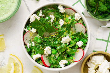Spring Pea salad with radishes, feta  and mint. in ceramic bowl. selective focus