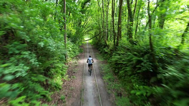 Aerial view tracking a cyclist traveling along the greenway, on an old railway tracks of Lieres coal mine, Siero, Asturias, Spain