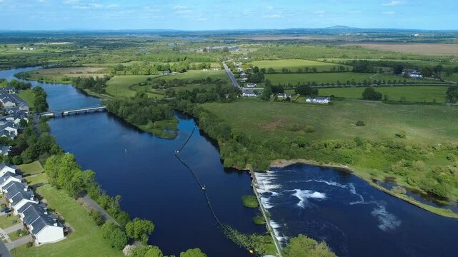 A panoramic view of the River Shannon at Tarmonbarry County Roscommon, Ireland captures the calm river winding through lush green fields, showcasing the beauty of nature and serene rural life.