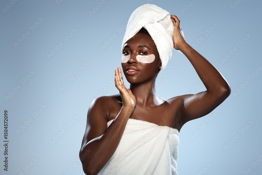 Poster skincare routine featuring a woman applying eye masks while wrapped in a towel in a bright studio se