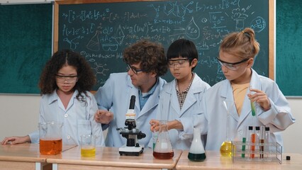 Skilled child hold tube while doing experiment while smart teacher explain and analyze chemical...