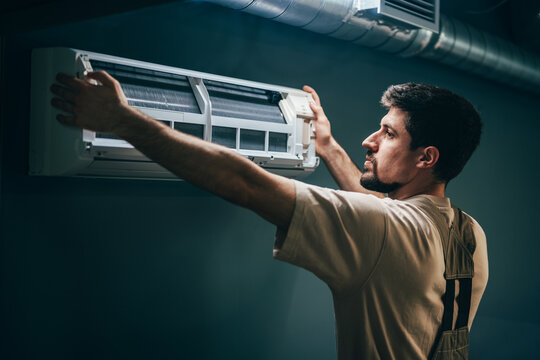 Technician installs air conditioning unit in residential space during daylight hours