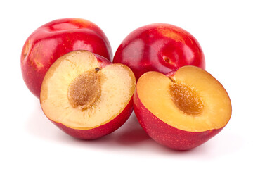 Red plums with pit and halves, isolated on white background.