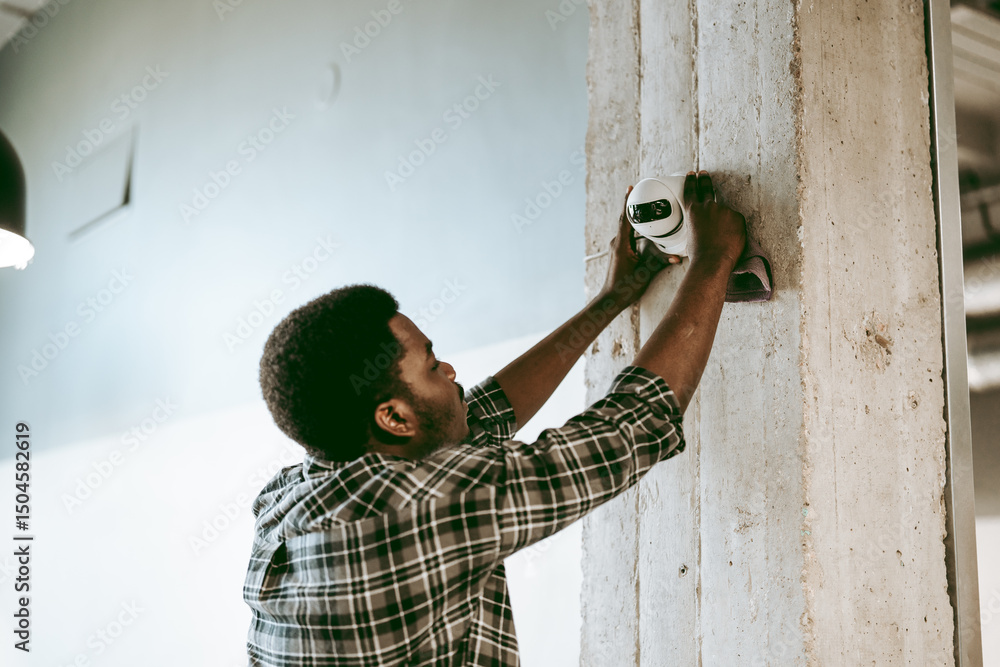 Aufkleber skilled worker installing security camera on concrete pillar in modern workspace in the afternoon