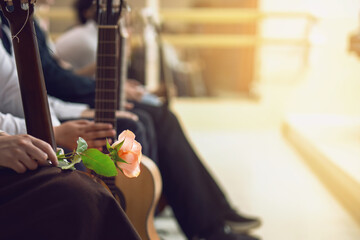 Guitar competition contestants holding instruments await results, with one holding a red rose in...
