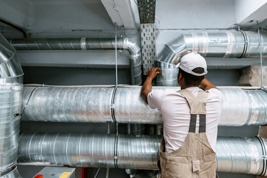 Skilled worker installing metal ductwork in a commercial building during a maintenance project
