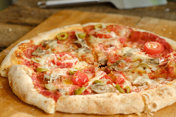 Homemade baked sliced pizza with mushrooms and olives on wooden table