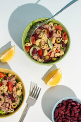 Balanced diet - Healthy tuna salads mixed with macaroni, lettuce, cheery tomato, peas and beans cucumber on white background. 
