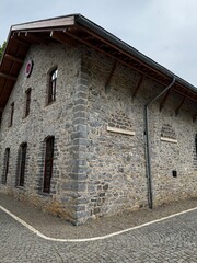 Historic stone building with a wooden roof and cobblestone pavement, photographed from a low-angle perspective. Ideal for themes related to architecture, heritage, and travel.