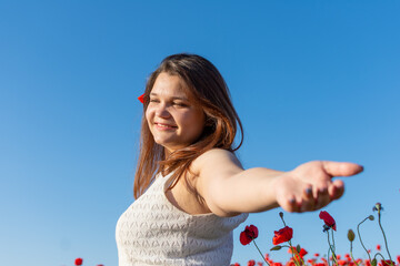A joyful woman with arms outstretched in a field of red flowers