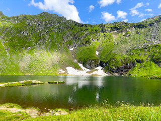 A picturesque small lake surrounded by majestic mountains on a sunny day