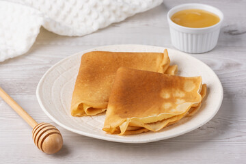 Traditional Russian pancakes with honey on a white wooden table