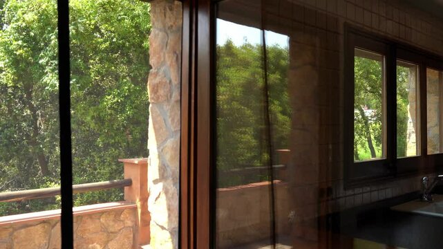 Mosquito net waving in the wind in a kitchen window of a country house with trees in the background