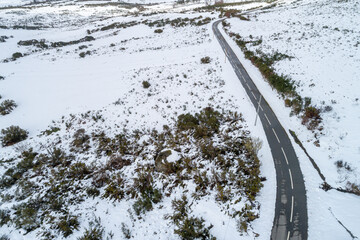 isolated country road through a white snowy vista, aerial drone view