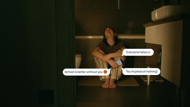 Wide shot with VFX effects of desolate young Caucasian girl in pyjamas crouching on floor in bathroom, clutching smartphone, sobbing due to cyberbullying, with hate messages popping up around her