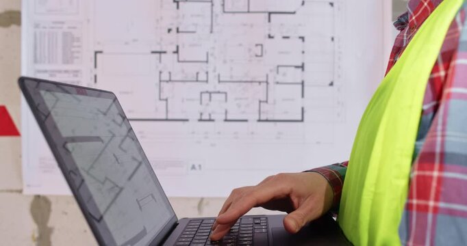 Engineer presses keys on laptop entering data about apartment ayout. Specialist uses program to speed up work processes of renovation and to automate problem solving