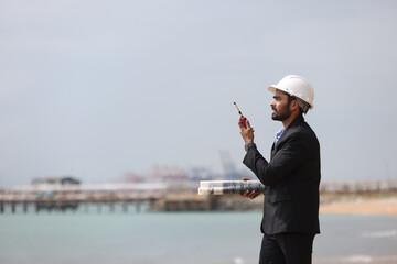 Business Man or Investor with black suit and safety hat working with drawing and digital tablet at...