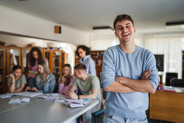 Fototapeta premium Portrait of arm crossed handsome man student stand in the school library
