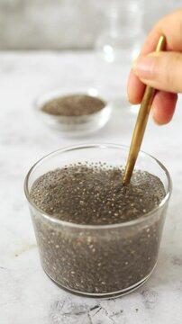 Vertical video showing chia seeds suspended and expanding in water, highlighting their natural gel-like texture.
