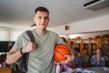 handsome man student stand with backpack and basket ball in library
