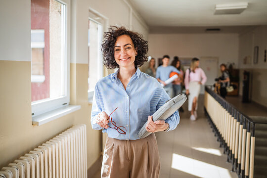 mature female teacher walk confidently at school hallway with handbag