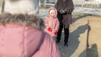 Grandmother playing with her granddaughter on the playground in the park in winter