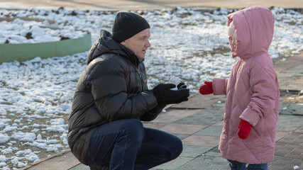 Grandfather playing with her granddaughter on the playground in the park in winter
