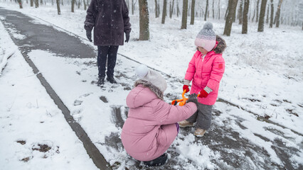 Grandmother with grandchildren in warm clothes playing outdoors in winter park, enjoying snowy...
