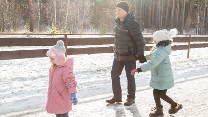 Little girls with her grandfather walking in park on snowy winter day