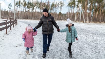 Little girls with her grandfather walking in park on snowy winter day