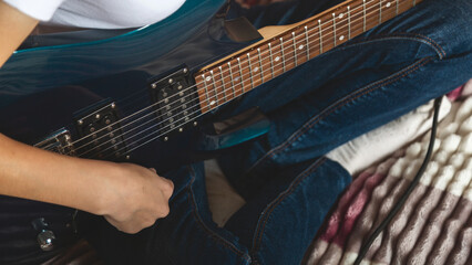 Close-up of girl's hands playing electric guitar indoors