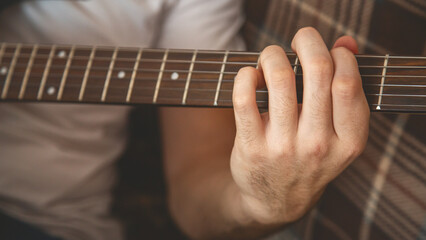 Man's hands playing electric guitar, close up at home