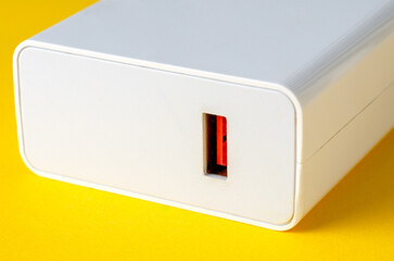 White electrical plug adapter on yellow background, close-up view
