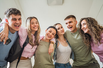 Portrait of hugged happy high school friends on school hallway