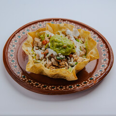Fresh Mexican taco salad with ground beef, lettuce, cheese, and vegetables served in a crispy tortilla bowl. Isolated on a white background.