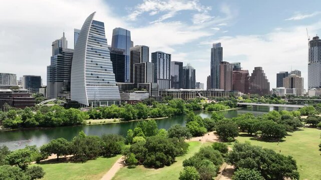 Daytime Austin downtown & Lady Bird Lake. Green trees, lawn, running people, kayaks, busy traffic. Vibrant Texas urban landscape.