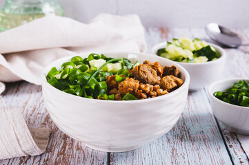 Buckwheat porridge with meat, cucumber and chives in a bowl on the table