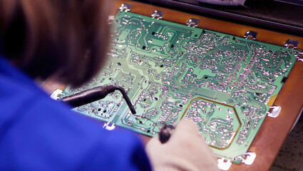 Detailed work on a printed circuit board in a technology workshop during daytime