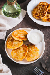Appetizing potato fritters and sour cream on a plate on the table vertical view